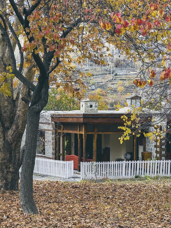 A traditional stone guesthouse under autumn leaves in Hunza