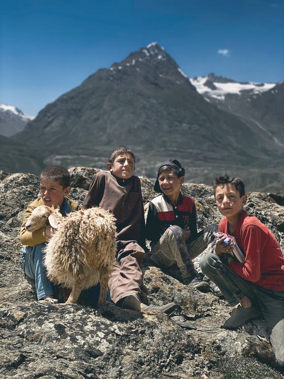 Local children with a lamb on rocks below a peak