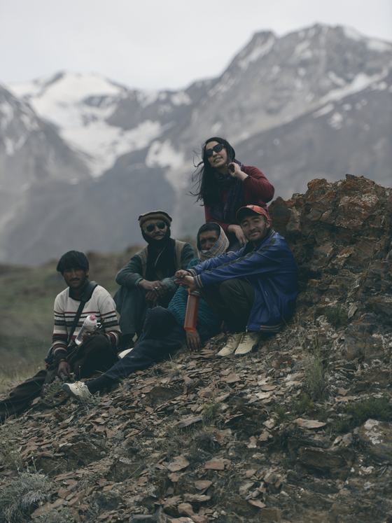Porters and a traveller resting on a rocky slope