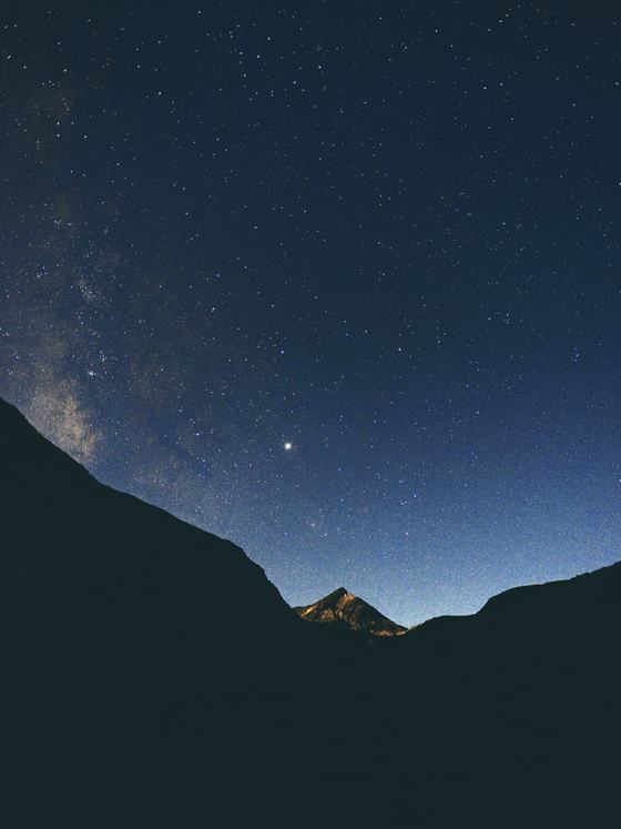 The Milky Way above a dark mountain valley