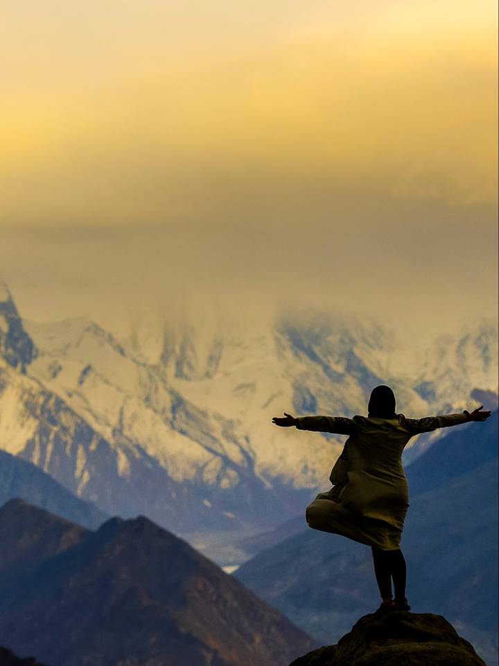 A traveller with arms outstretched on a rock at Eagle's Nest above Hunza