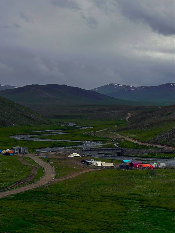 Tents and jeeps by a river crossing on the Deosai plains