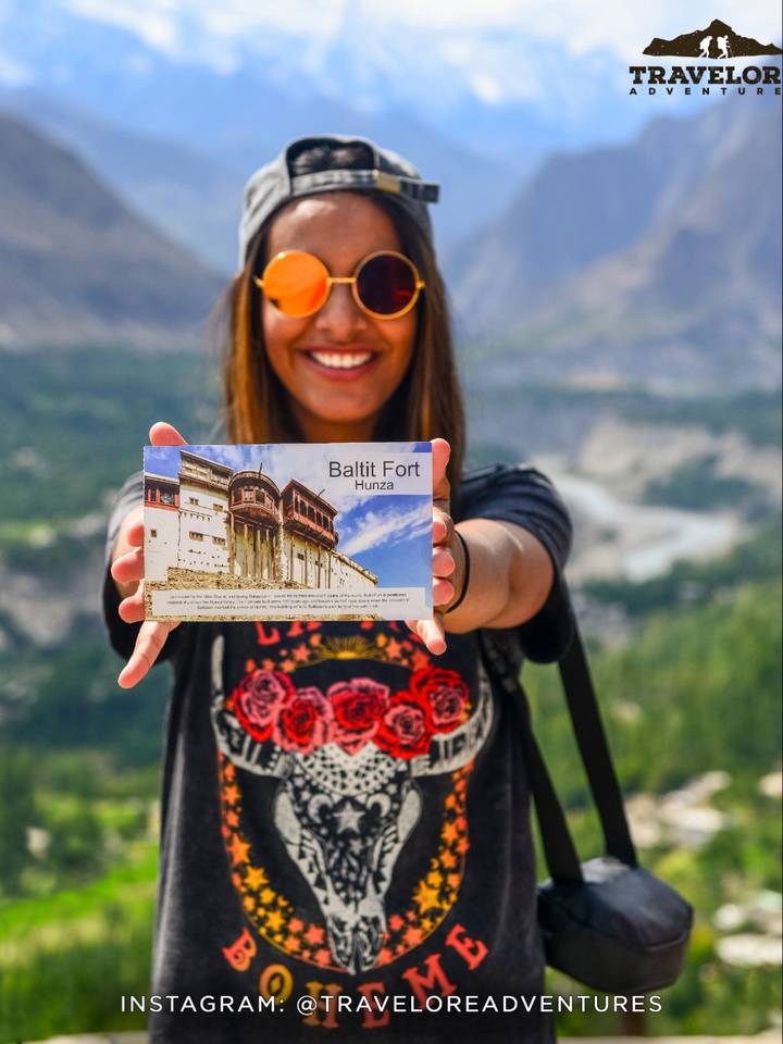 A traveller holding a Baltit Fort postcard above the Hunza valley