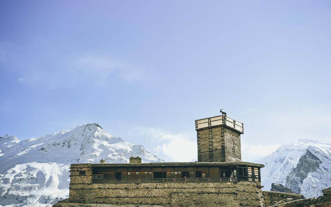 Altit Fort tower with an ibex statue against snow peaks