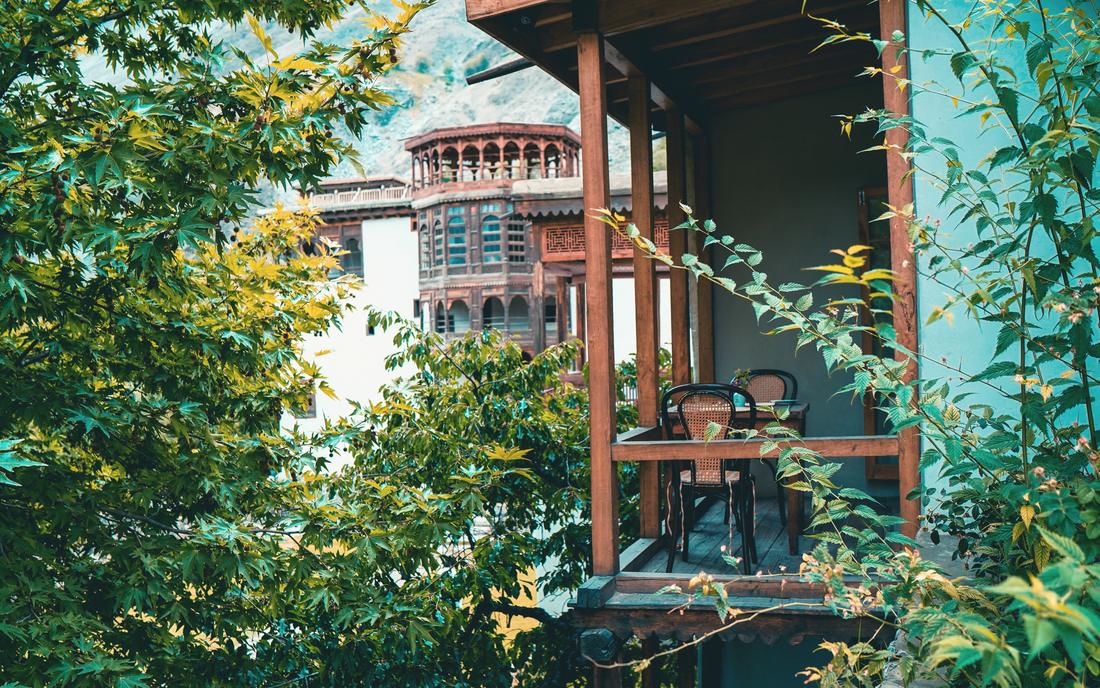 A wooden balcony among plane trees facing Shigar Fort